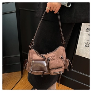 Detail of vintage brown suede shoulder bag featuring tassel zippers and multi-pocket design