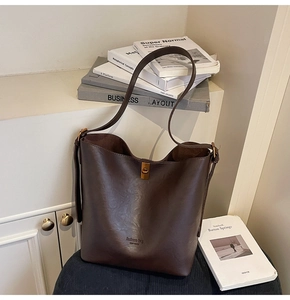 Detail der dunkelbraunen Beuteltasche aus Leder mit Litschi-Struktur und Goldverschluss