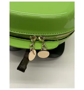 Détail des doubles fermetures éclair dorées et tirettes rondes sur sac en cuir verni fluo