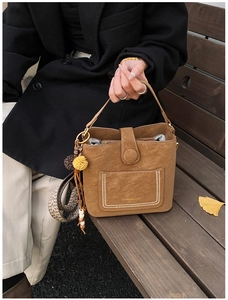 Detail of dark brown suede bucket bag featuring ethnic style woven strap and tassels