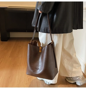 Detailansicht der dunkelbraunen Beuteltasche mit goldener Schnalle und Logo-Print