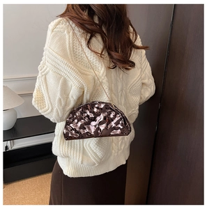 Rear view of bronze metallic pleated half-moon bag with gold chain strap on model