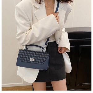 Detail of navy blue quilted crossbody bag with metal twist lock worn by a model