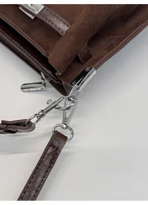 Makroaufnahme einer dunkelbraunen Ledertasche mit polierten silbernen Schnallen