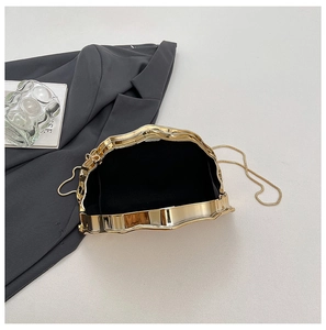 Detail showing wavy gold metal clutch with black fabric lining and elegant chain strap