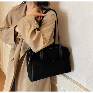 Model wearing a black suede shoulder bag with button pocket on a khaki trench coat