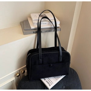 Detail view of black suede tote bag with slim shoulder straps and snap button pocket