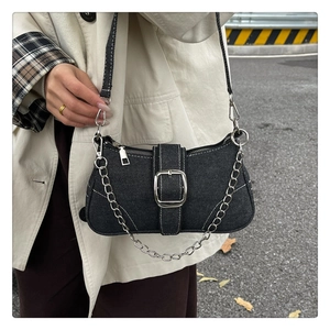 Détail du sac baguette en denim noir avec boucle métallique et chaîne argentée épaisse
