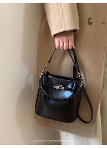Detailansicht der schwarzen Leder-Beuteltasche mit Metalldrehverschluss und Tragegriff