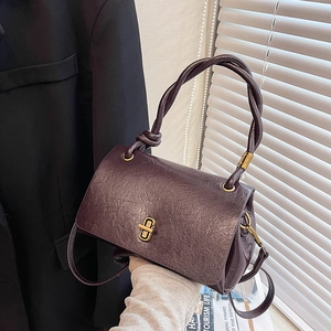 Deep purple vintage pleated handbag with gold turn-lock and woven handle on black suit