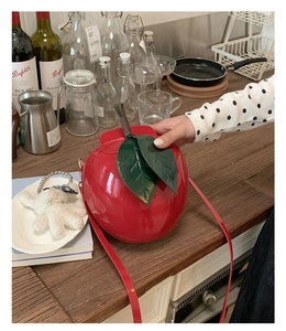 Détail du sac à bandoulière créatif en forme de pomme rouge avec feuilles sur table en bois