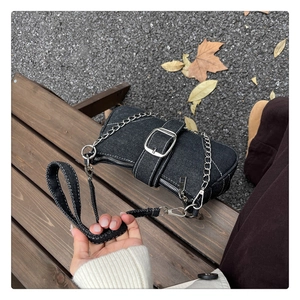 Détail du sac baguette en jean noir avec surpiqûres blanches et boucle argentée élégante