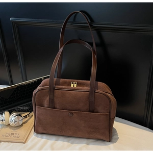 Detail of dark brown suede shoulder bag with dual zippers and decorative pocket