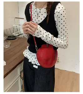 Détail du mini sac bandoulière rouge en forme de pomme avec décor de feuilles vertes