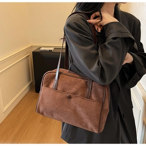 Detail of vintage brown suede shoulder bag worn by model in cozy interior setting