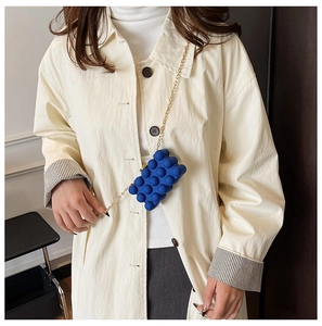 Mini Klein Blue box bag with 3D sphere texture and gold chain worn with a beige coat