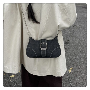 Détail d'un sac bandoulière Y2K en denim noir avec une grande boucle métal et chaîne argent