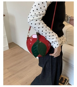 Détail du sac à bandoulière en forme de pomme rouge en cuir verni avec feuilles vertes