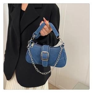 Détail du sac baguette en jean bleu foncé avec chaîne argentée et boucle métallique