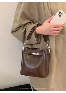 Detail der Retro-Eimertasche aus dunkelbraunem Leder mit geflochtenem Griff und Verschluss