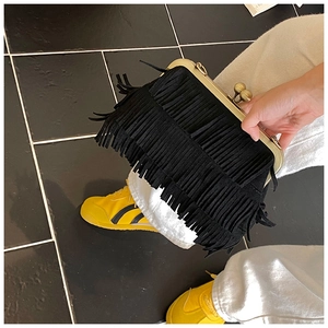 Détail d'un sac à franges noir vintage avec fermoir doré et pampilles en daim multicouches