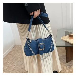 Détail macro du sac baguette en denim bleu avec surpiqûres blanches et boucle argent