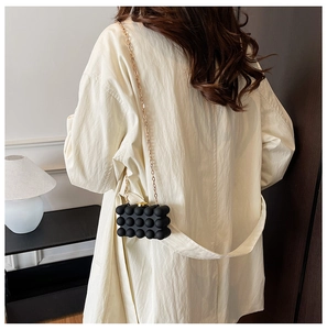 Detailed back view of a chic black bubble texture crossbody bag with gold chain strap