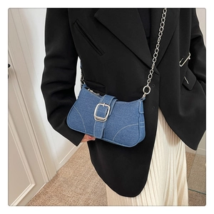 Détail du sac baguette en jean bleu foncé avec boucle argentée et surpiqûres blanches
