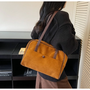 Caramel suede tote bag with dark brown handles shown on model in a modern room