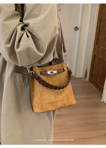 Detail einer Retro-Wildledertasche mit geflochtenem Griff und silbernem Drehverschluss