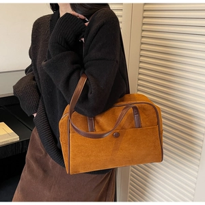 Macro detail of caramel suede hobo bag with dark leather trim and buckle accent