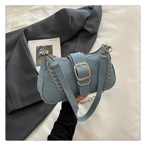 Détail du sac baguette en denim bleu clair avec boucle métallique argentée et chaînette