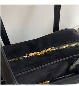 Close-up of golden dual zipper detail on black suede leather shoulder bag