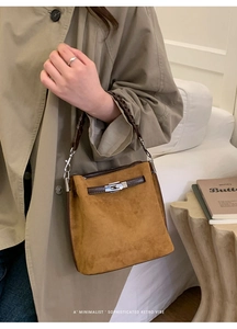 Details einer braunen Wildleder-Beuteltasche mit klassischem Drehverschluss aus Metall