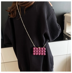 Detail of purple acrylic mini box bag with 3D bubble texture and gold chain strap