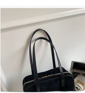 Close-up of black suede shoulder bag with gold zipper and laptop for work commute