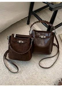 Detailaufnahme brauner Beuteltaschen mit geflochtenen Griffen und silbernem Metallverschluss