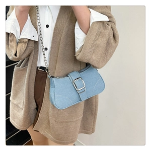 Détail du sac baguette en jean bleu clair avec boucle argentée et chaîne en métal