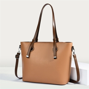 Detail of light brown lychee grain leather tote bag with dark brown strap and silver hardware