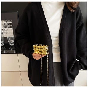 Detail of elegant gold bubble texture clutch bag with metallic chain strap on model