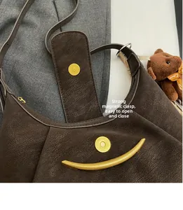 Detail of dark brown leather underarm bag featuring a crescent metal bar and magnetic snap