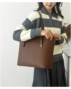 Detail of dark brown tote bag showing textured litchi grain leather and silver hardware