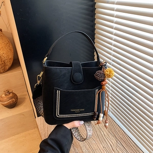 Black leather bucket bag with bohemian wide strap and tassel detail shown in lifestyle view