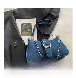 Détail du sac bandoulière en jean bleu avec boucle argentée et surpiqûres blanches