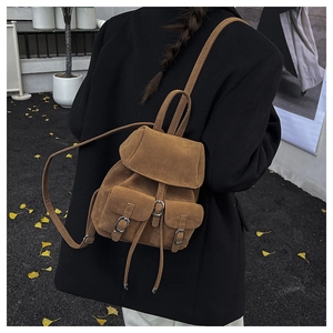 Close-up of brown suede vintage backpack with metal buckles shown in an autumn setting