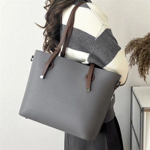 Detail of grey leather tote bag showing side metal hook for detachable shoulder strap
