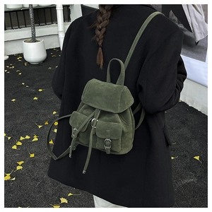 Detail of dark green suede backpack featuring drawstring closure and vintage metal buckles