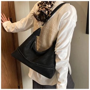 Detail view of large black crescent shoulder bag with hand-stitched texture and gold hardware