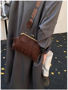 Détail du sac à franges en daim marron foncé avec bandoulière bohème sur feuilles d'automne