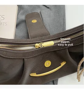 Close-up of smooth gold zipper and magnetic snap on dark brown lychee texture leather bag